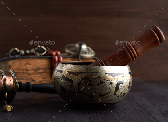 Tibetan singing copper bowl with a wooden clapper on a brown wooden table - Stock Photo - Images