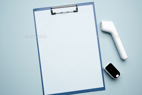 Paper clipboard and plastic white electronic non-contact thermometer and blood oxygen meter
