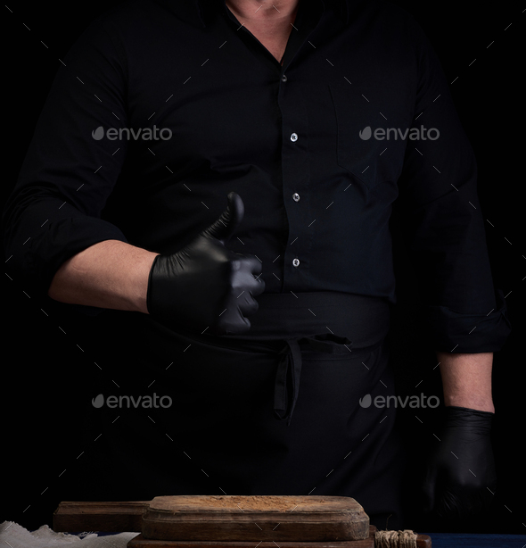 Male cook in black uniform and black latex gloves shows like approval