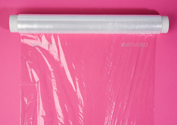 Roll of transparent cling film on pink background