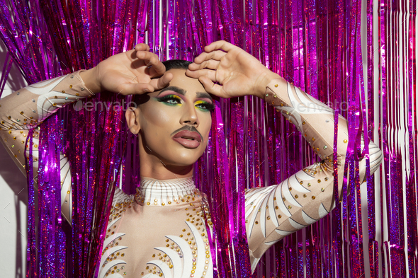 portrait of beautiful young man in drag queen makeup and colorful background