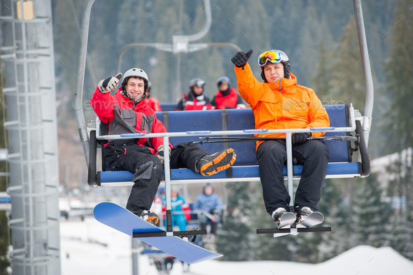 Skier and snowboarder riding up on ski lift