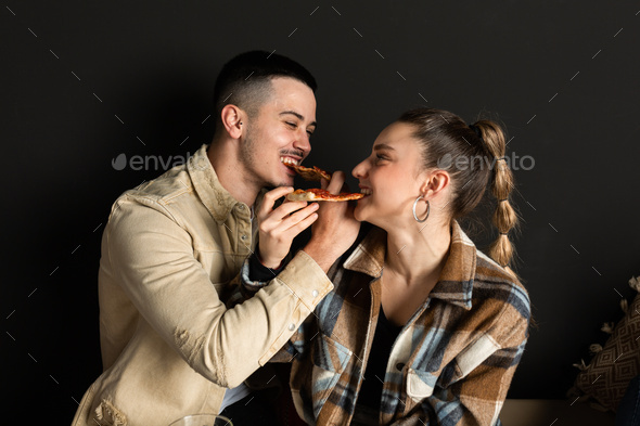 boy and girl couple share 2 slices of pizza by intertwining arms