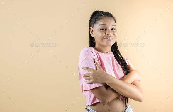 young african woman hugs herself, happy self love, yellow background