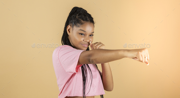 Image of a young African boxer throws punch, strong woman, yellow background