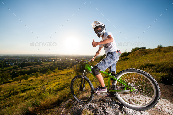 Cyclist with mountain bike on the hill under blue sky