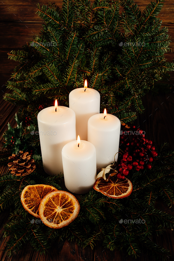 four burning white advent candles in advent wreath decoration on wooden dark background. Stock