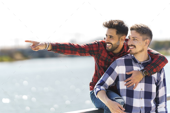 gay points out a spot to her boyfriend sitting on the railing of a jetty