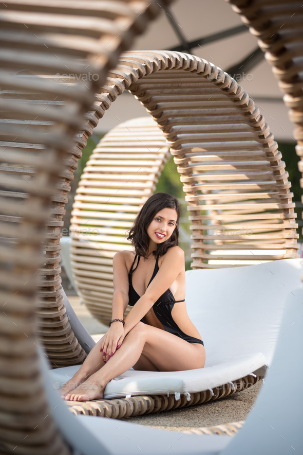 lady sitting on original wooden lounger with white mattress on the luxury resort.