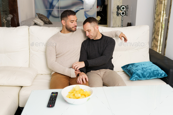 Gay couple chilling on sofa at home