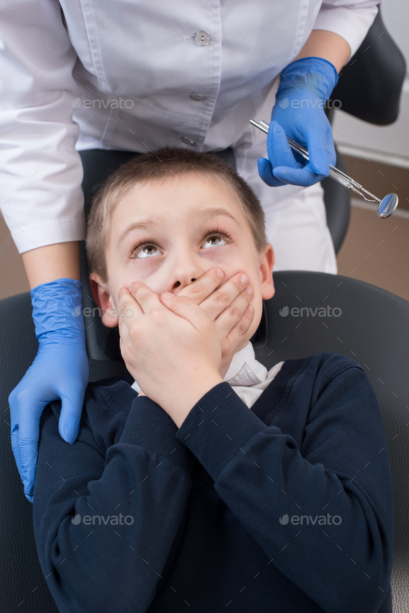 Boy frightened by dentists covers her mouth and looks for him