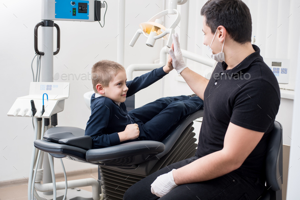 Pediatric dentist gives five young boy, congratulate patient for a successful treatment