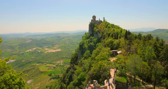 Towers On Top Of The San Marino Mountains With Tourist Trekking In Italy. Aerial Tilt-down Shot alt