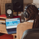 Musician with headphones sitting at desk with laptop while recording new song in the music studio - PhotoDune Item for Sale
