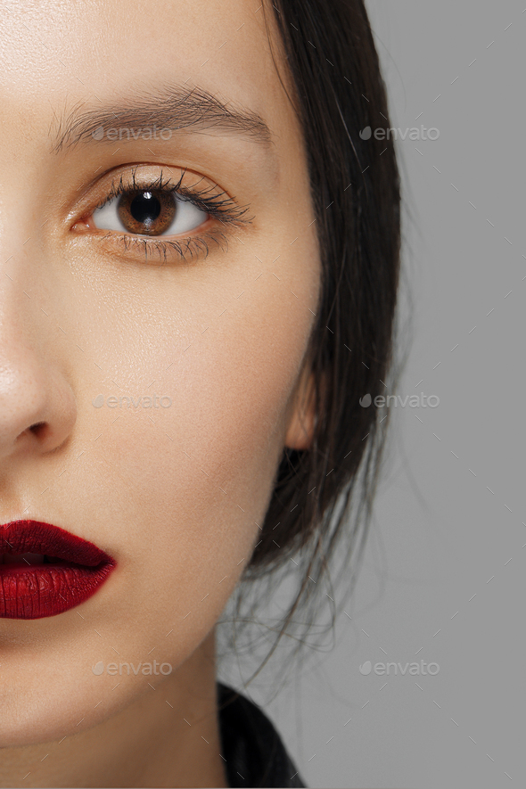 half face of fashion model with tan makeup and red mat lips