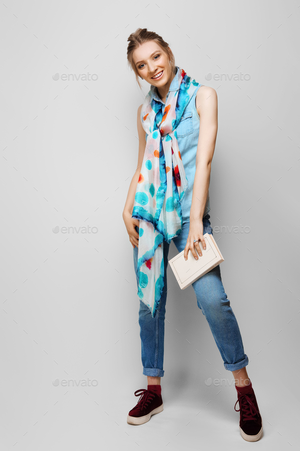 Pretty girl in rolled up jeans, gumshoes and colorful silk scarf with book in hand.