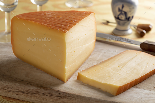 Piece of Dutch Kernhem cheese and a slice on a cutting board - Stock Photo - Images