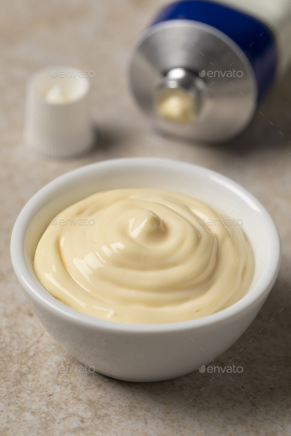 Bowl with Mayonnaise and a tube of mayonnaise in the background - Stock Photo - Images