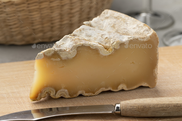 Piece of French Mountain Abbey cheese on a cutting board close up - Stock Photo - Images