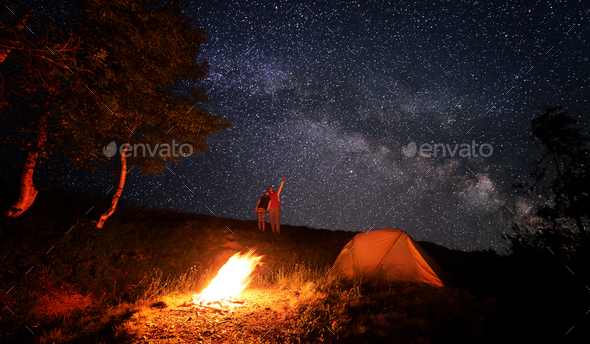 Camping fire and tent under the amazing starry sky with lot of shining ...