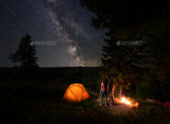 Rear view of young couple looking at starry sky with bright milky way