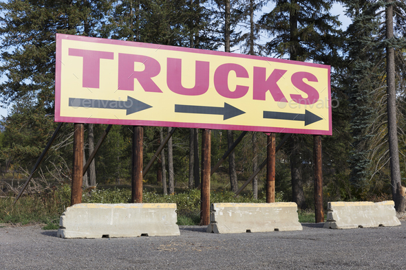 TRUCKS billboard sign with directional arrows at a truckstop parking lot.