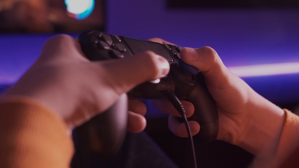 Detalle de mando y manos de adolescente jugando a videojuegos.