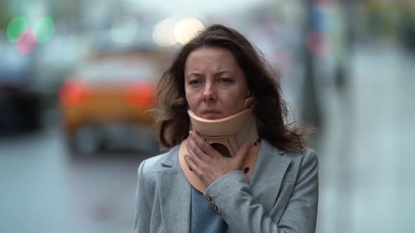 Sad Woman with Neck Ache Is Walking on City Street, Wearing Orthopedic Collar, Curing of alt