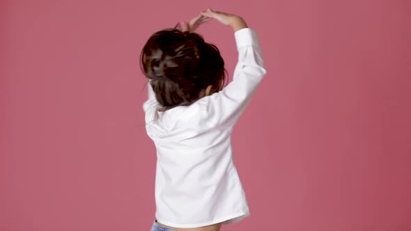 Little Child Girl in White Shirt Dancing on Pink Background