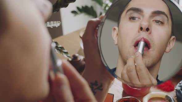 Transgender Woman Looking in Mirror and Putting on Lipstick alt
