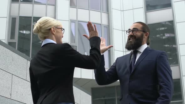 Bearded Businessman Giving High-Five to Female Colleague, Happy About Success