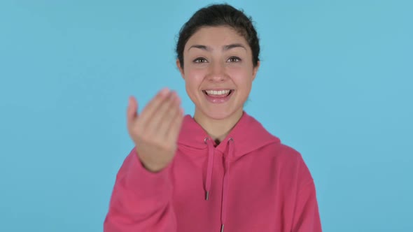 Indian Girl Pointing at the Camera and Inviting  Blue Background alt