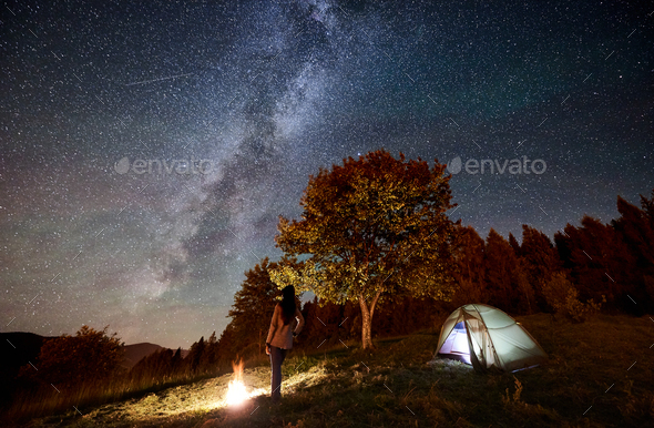Woman resting at camp and tent under under night starry sky