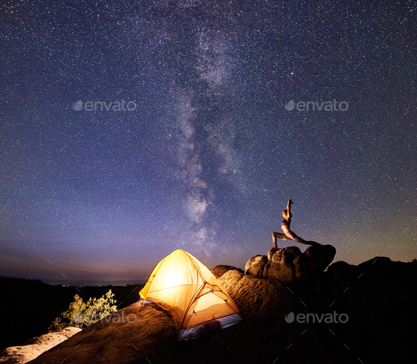 Camping at night on rock formation. Tourist tent and woman doing yoga on  mountain top Stock Photo by anatoliy_gleb