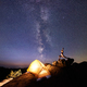 Camping at night on rock formation. Tourist tent and woman doing