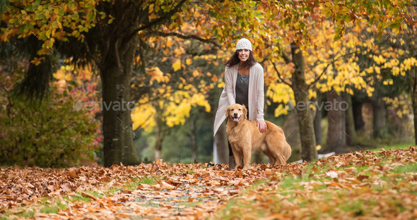 Pretty woman with her Golden Retriever Dog at a park in the Fall