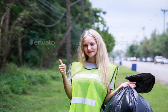 Volunteers, Caucasians are helping to pick up waste by garbage bags beside the road.