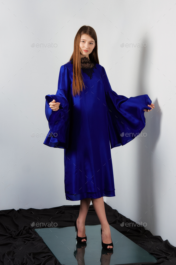 Attractive fashion model in blue silk dress with butterfly sleeves