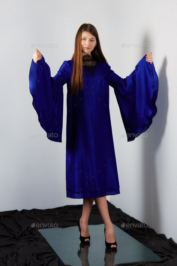 Attractive fashion model in blue silk dress with butterfly sleeves