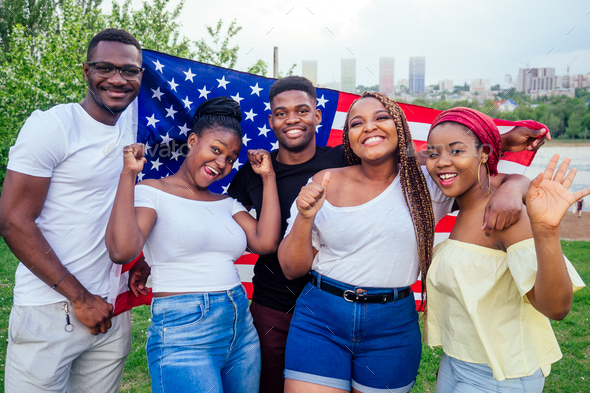 Group of girls and boys smiling with American flag in spring park autumn evening