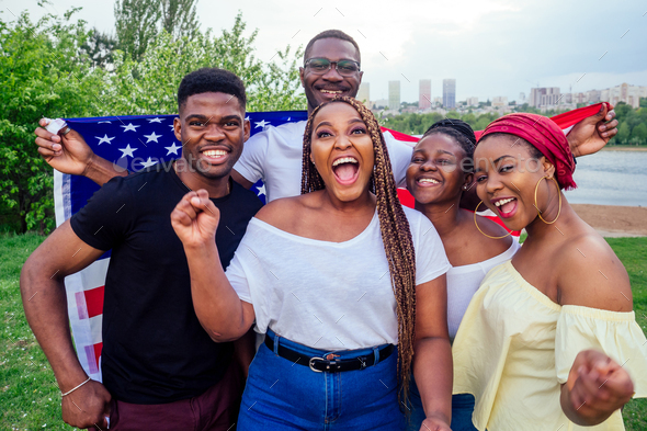 Group of girls and boys smiling with American flag in spring park autumn evening