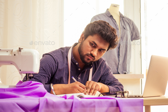 handsome indian tailor man In a stylish shirt workinh with violet cotton textile
