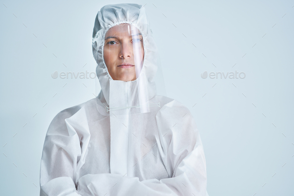 Woman in bio-hazard suit and face shield on white background.