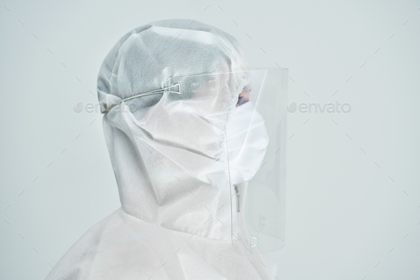 Woman in bio-hazard suit and face shield on white background.