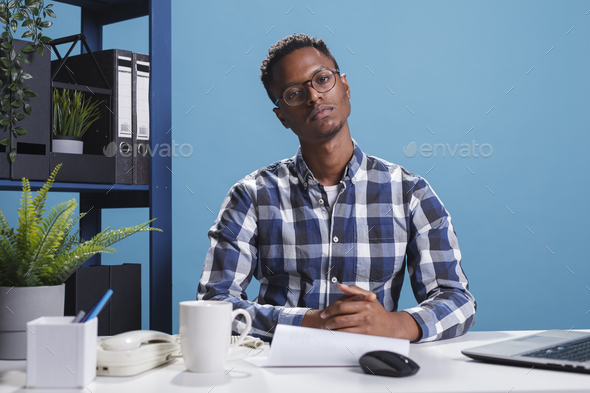 Development agency confident accountant sitting in workspace while looking at camera.