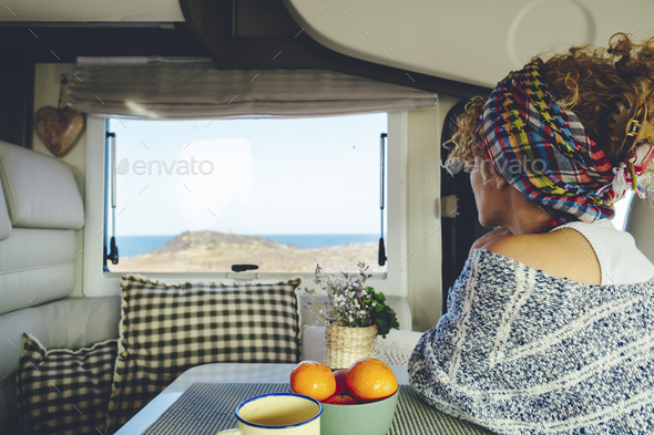 Back view of a woman looking outside the window inside a camper van. Van life and off grid life