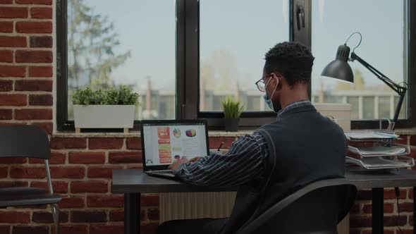 African American Person with Face Mask Working on Business Growth alt