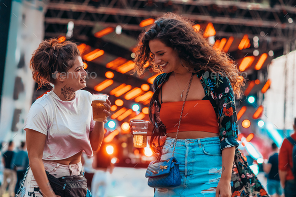 Two beautiful friends drinking beer and having fun on a music festival - Stock Photo - Images