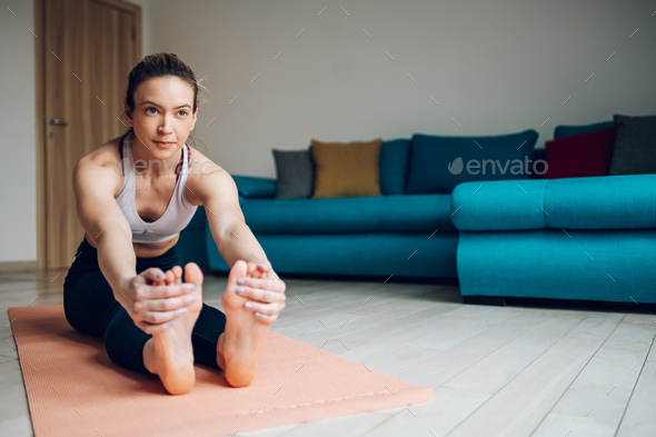 Woman reaching out to touch her toes while training yoga at home
