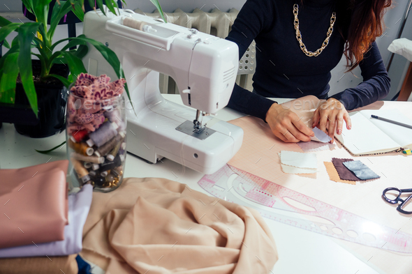 seamstress writes in a notebook. the tailor creates a collection of outfits.